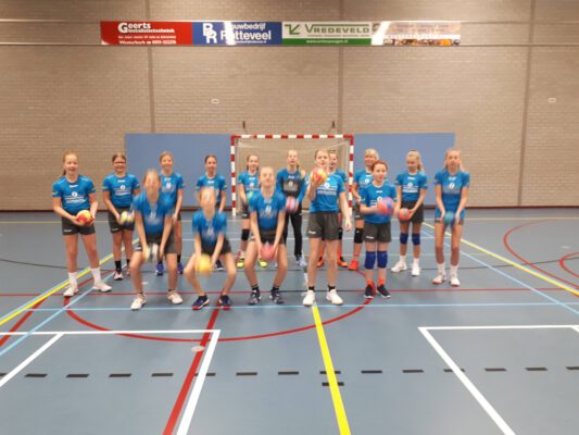 Afbeelding deelnemers handbalschool Midden-Drenthe gooien bal omhoog